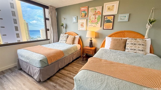 bedroom with a water view, wood-type flooring, and a textured ceiling