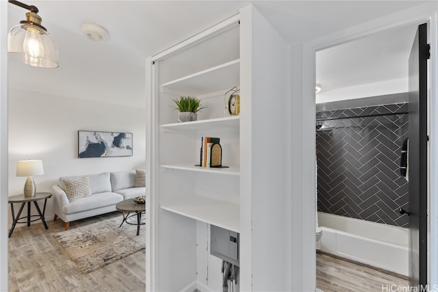 interior space featuring hardwood / wood-style floors, toilet, and tiled shower / bath combo