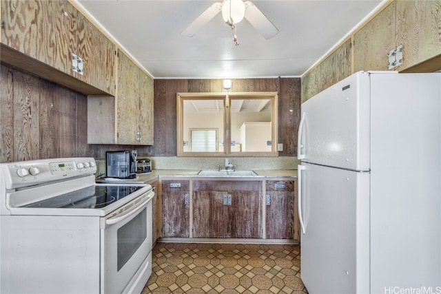 kitchen featuring wood walls, white appliances, ceiling fan, and sink