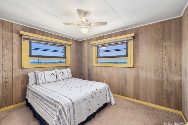 bedroom featuring wood walls, ceiling fan, and carpet