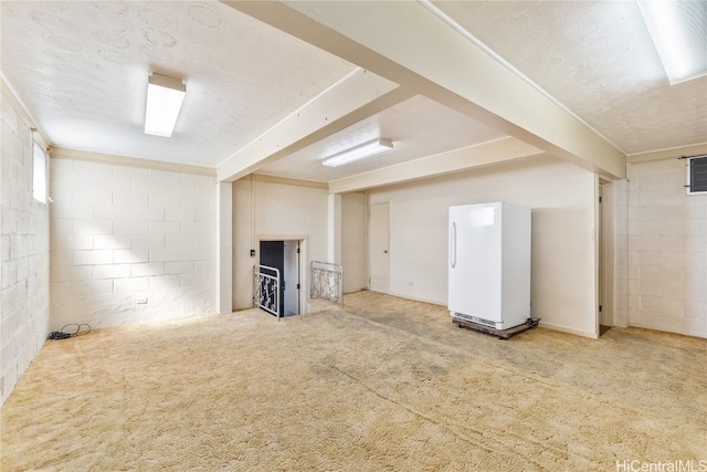 basement with a textured ceiling, white fridge, and carpet floors