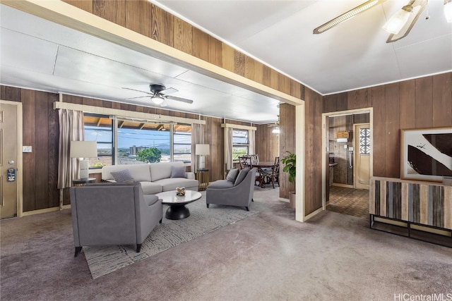 carpeted living room with wooden walls and ceiling fan