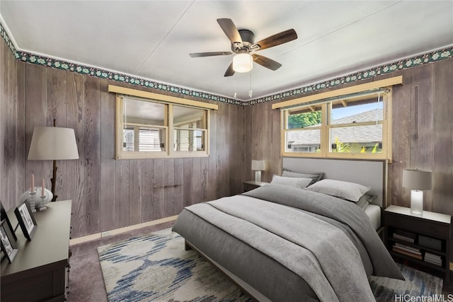 bedroom with ceiling fan and wooden walls