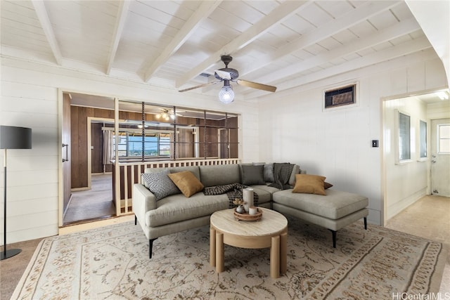 living room with wood walls, beamed ceiling, a healthy amount of sunlight, and light carpet