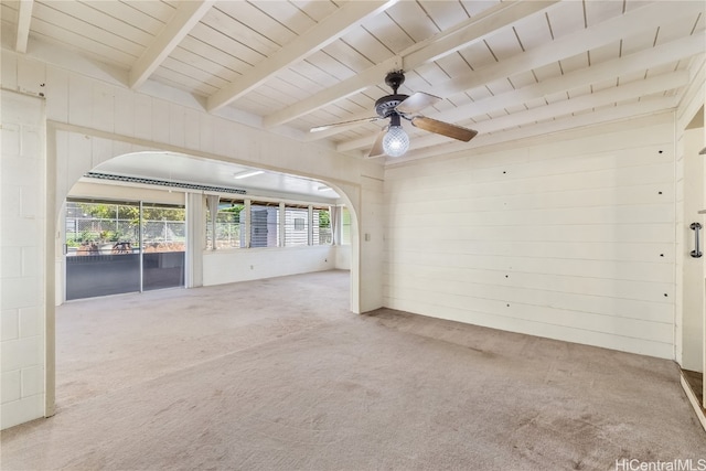 carpeted empty room with a wealth of natural light, wood walls, and beamed ceiling