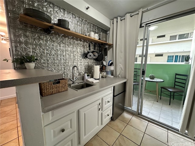 bar featuring white cabinets, sink, tasteful backsplash, and light tile patterned flooring