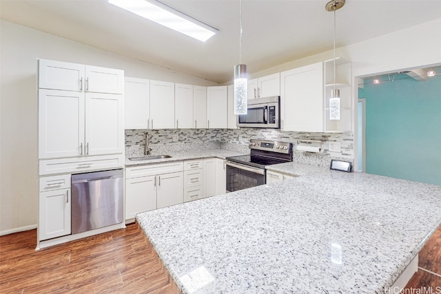 kitchen featuring sink, kitchen peninsula, appliances with stainless steel finishes, decorative light fixtures, and white cabinets