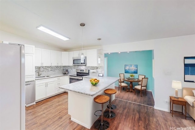 kitchen with sink, white cabinetry, appliances with stainless steel finishes, and decorative light fixtures