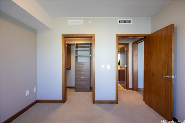 unfurnished bedroom with light colored carpet and a closet