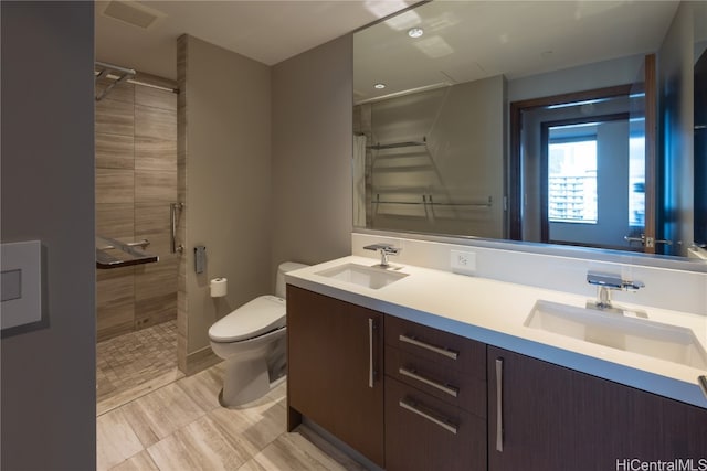 bathroom featuring a tile shower, vanity, and toilet