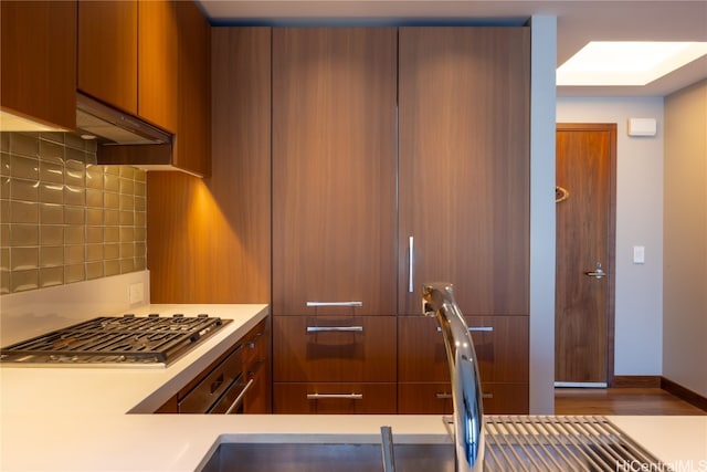 kitchen with hardwood / wood-style floors, stainless steel gas stovetop, and decorative backsplash