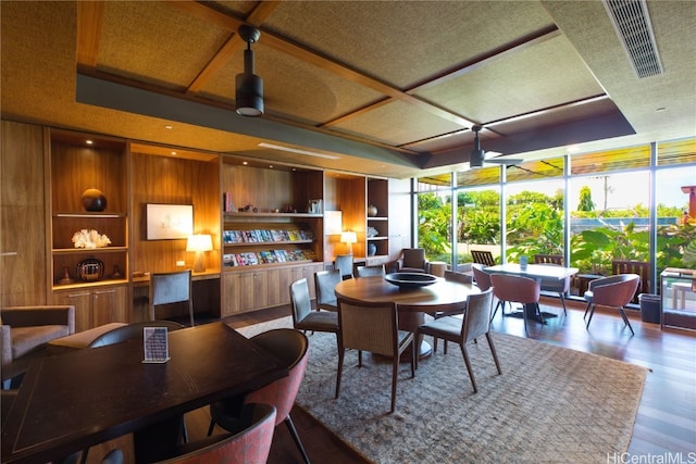 dining room featuring hardwood / wood-style floors, floor to ceiling windows, built in features, and wooden walls