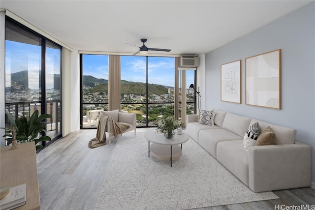 living room with hardwood / wood-style flooring, a mountain view, a wall unit AC, and a wall of windows