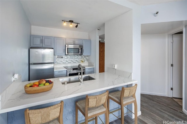 kitchen featuring dark wood-type flooring, stainless steel appliances, kitchen peninsula, and decorative backsplash