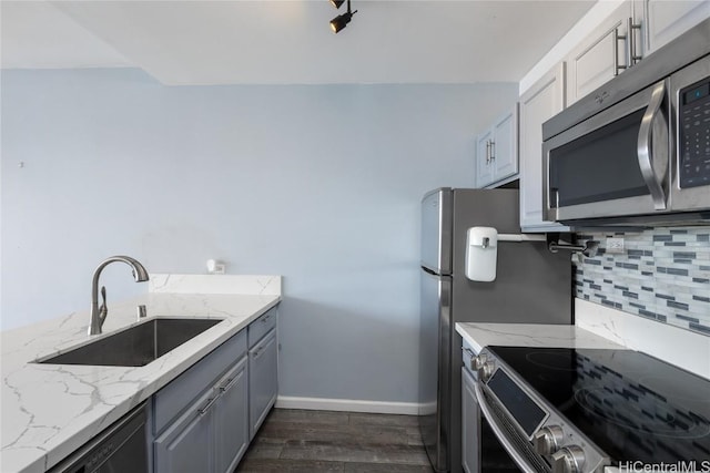 kitchen with stainless steel appliances, sink, backsplash, and light stone counters