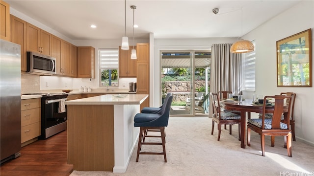 kitchen featuring appliances with stainless steel finishes, hanging light fixtures, a center island, and dark hardwood / wood-style flooring