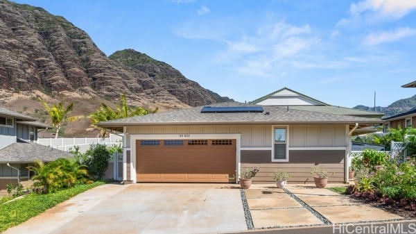 view of front of house with a mountain view, a garage, and solar panels