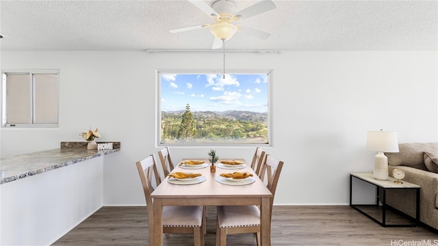 dining room with a textured ceiling, hardwood / wood-style flooring, and ceiling fan