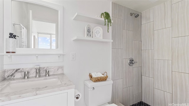 bathroom with toilet, vanity, and a tile shower