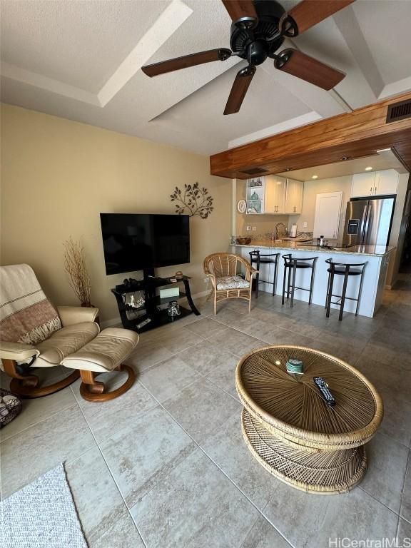 living area with light tile patterned floors, ceiling fan, and visible vents