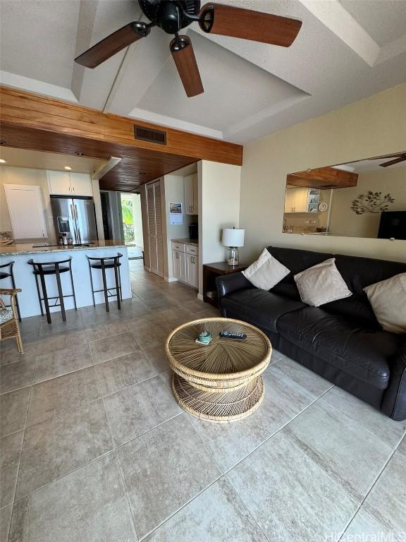 living room with a ceiling fan, visible vents, and light tile patterned floors