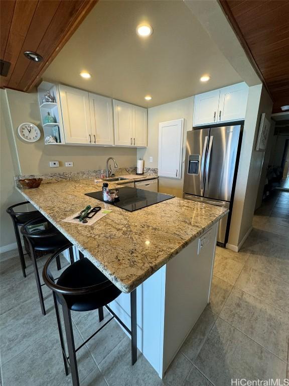 kitchen featuring a breakfast bar, white cabinets, stainless steel refrigerator with ice dispenser, and open shelves