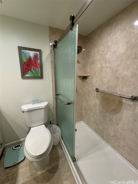 full bathroom with a stall shower, baseboards, tile patterned flooring, and toilet