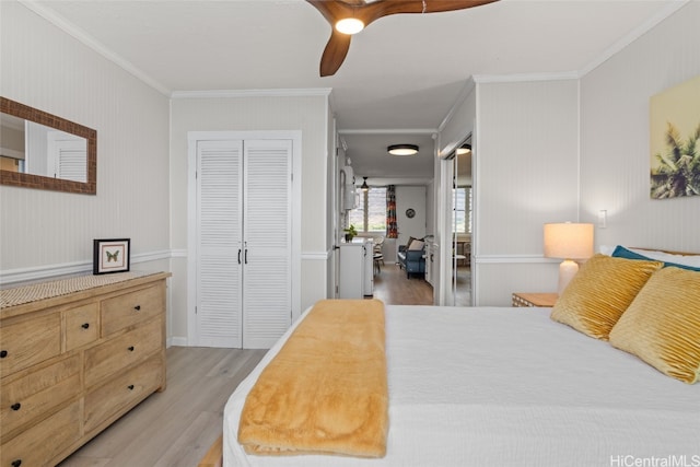 bedroom featuring light wood-type flooring, ceiling fan, a closet, and crown molding