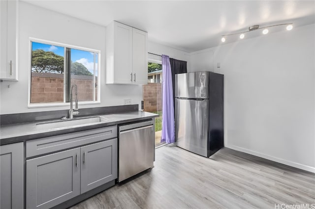 kitchen with light wood-type flooring, stainless steel appliances, gray cabinets, and sink