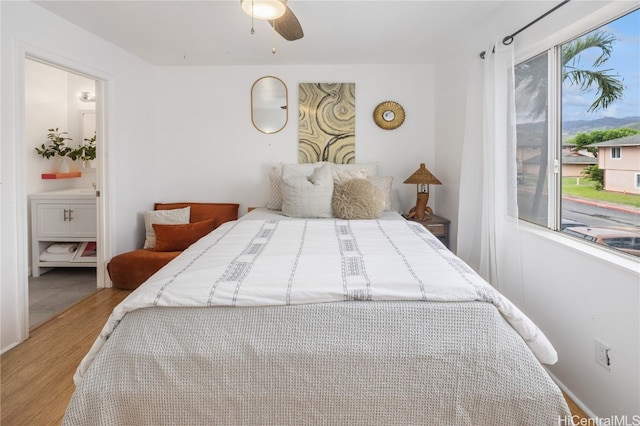 bedroom featuring connected bathroom, ceiling fan, and wood-type flooring