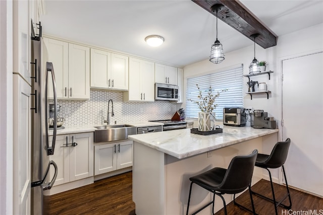 kitchen with dark wood-type flooring, white cabinets, sink, hanging light fixtures, and stainless steel appliances