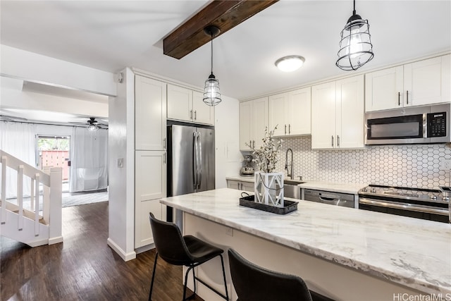 kitchen featuring appliances with stainless steel finishes, ceiling fan, pendant lighting, white cabinets, and dark hardwood / wood-style floors