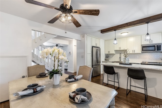 dining space featuring sink, beamed ceiling, and dark wood-type flooring