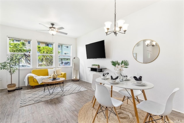 dining area with ceiling fan with notable chandelier and light wood-type flooring