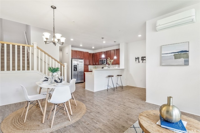 dining room with an AC wall unit, a chandelier, and light hardwood / wood-style flooring