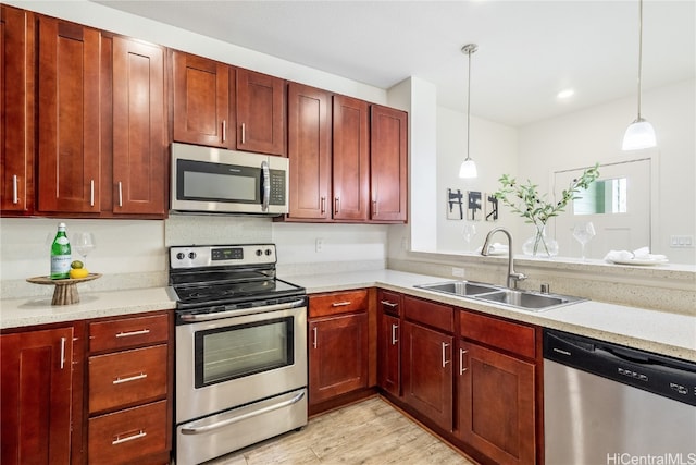 kitchen with pendant lighting, light hardwood / wood-style floors, appliances with stainless steel finishes, and sink