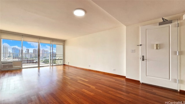 empty room with a wall of windows, wood-type flooring, and plenty of natural light