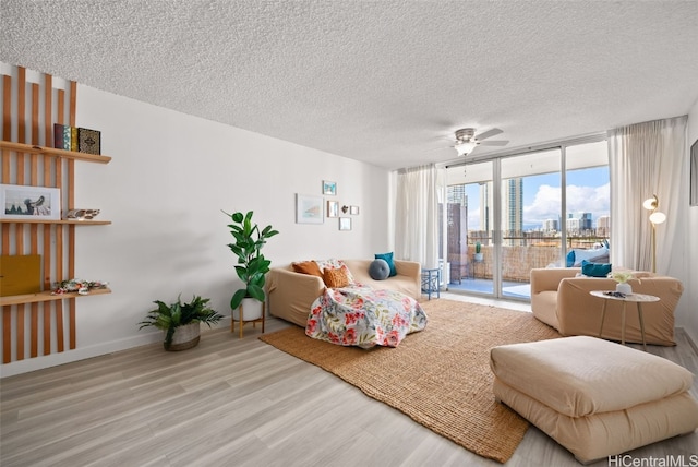 bedroom featuring light wood-type flooring, floor to ceiling windows, a textured ceiling, access to outside, and ceiling fan