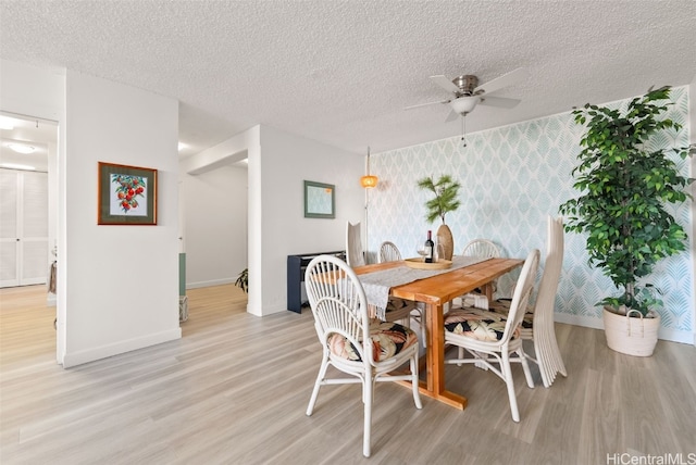 dining space with ceiling fan, light wood-type flooring, and a textured ceiling