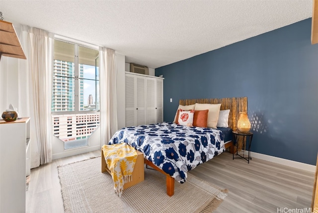 bedroom with a closet, a textured ceiling, and light wood-type flooring