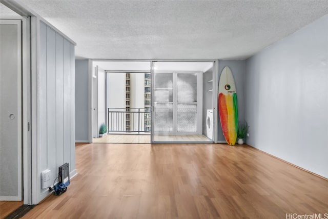 empty room with washer / dryer, light wood-type flooring, and a textured ceiling