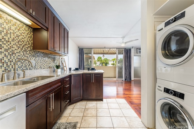 kitchen featuring decorative backsplash, sink, light stone countertops, light hardwood / wood-style flooring, and stacked washer / drying machine