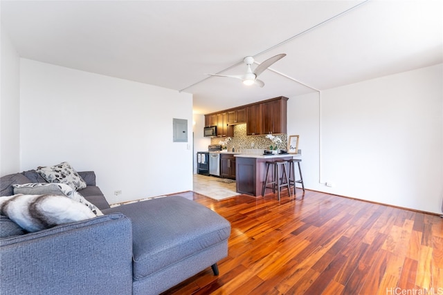 living room featuring ceiling fan, electric panel, and light hardwood / wood-style floors