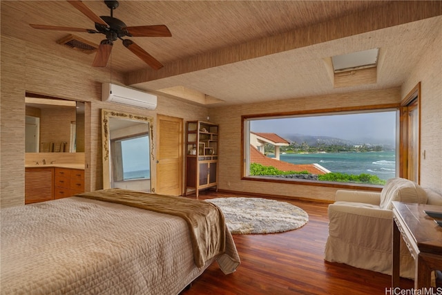 bedroom with a wall mounted air conditioner, dark hardwood / wood-style flooring, ceiling fan, sink, and a water view