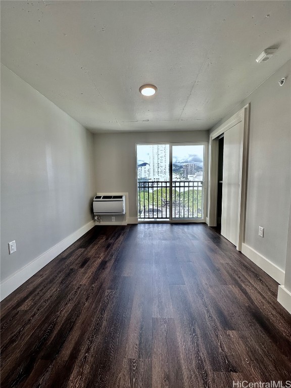 spare room featuring dark wood-type flooring and a wall mounted AC