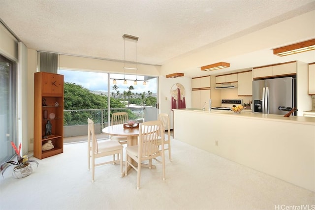 dining space featuring a textured ceiling, a healthy amount of sunlight, and light colored carpet