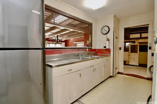 kitchen featuring white cabinetry, stainless steel refrigerator, and sink