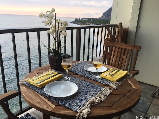 balcony at dusk featuring a water view