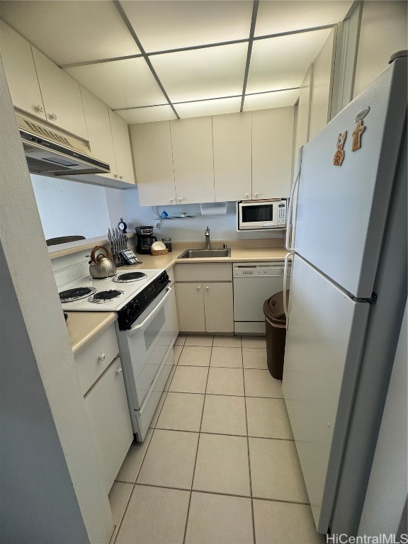 kitchen with white cabinets, light tile patterned floors, white appliances, and sink