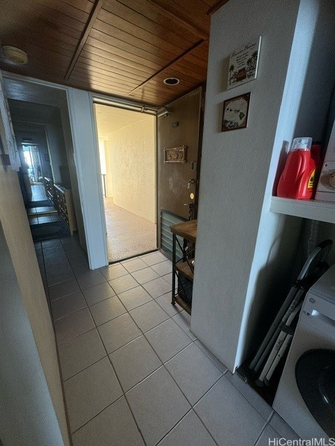 corridor featuring light tile patterned flooring, washer / dryer, and wood ceiling